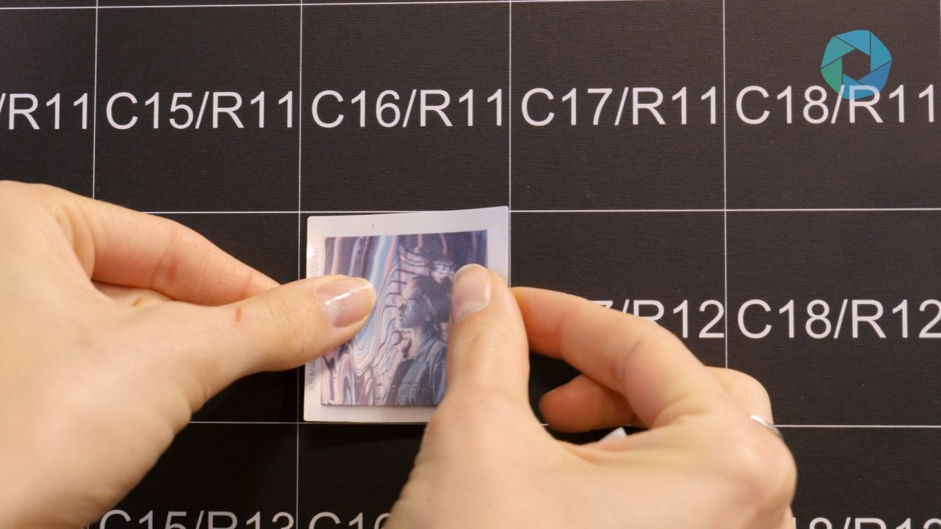 Fotosticker wird auf das nummerierte Raster der Fotomosaikwand geklebt